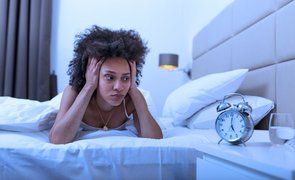 mulher na cama olhando para o relógio por não ter qualidade do sono