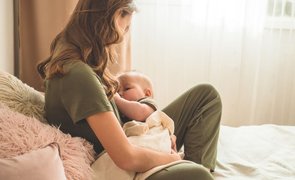 mulher com pijama de amamentação com bebê mamando